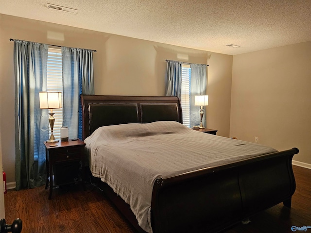 bedroom with a textured ceiling and dark hardwood / wood-style flooring