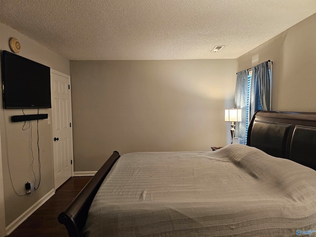 bedroom featuring a textured ceiling and dark hardwood / wood-style flooring