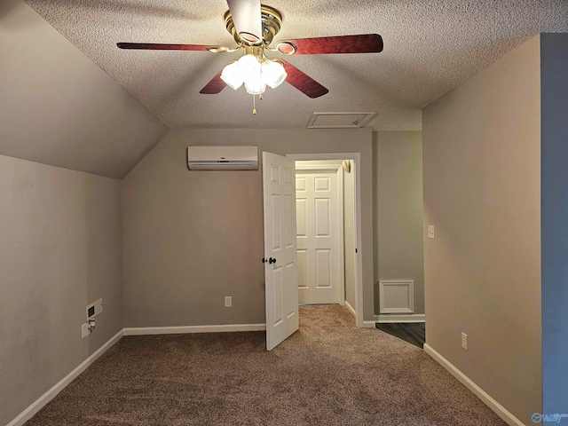 additional living space featuring a wall mounted AC, dark carpet, vaulted ceiling, a textured ceiling, and ceiling fan