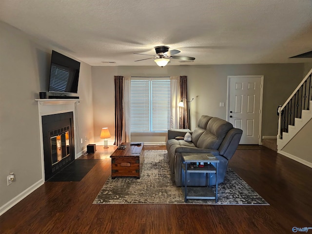 living room with a textured ceiling, ceiling fan, and dark hardwood / wood-style flooring