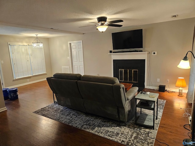 living room featuring hardwood / wood-style floors, a textured ceiling, and ceiling fan with notable chandelier