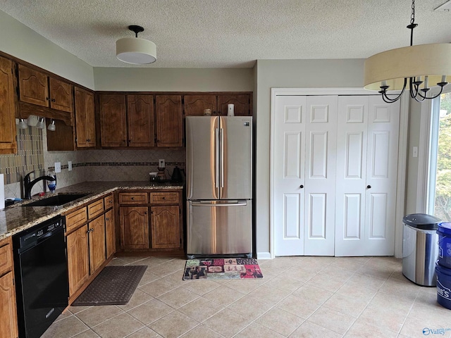 kitchen featuring decorative backsplash, black dishwasher, stainless steel fridge, sink, and a notable chandelier