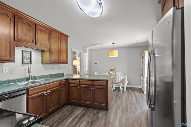 kitchen with dark wood-style floors, dark countertops, freestanding refrigerator, a sink, and a peninsula