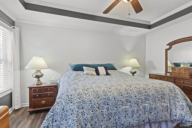 bedroom featuring baseboards, a raised ceiling, ceiling fan, wood finished floors, and crown molding