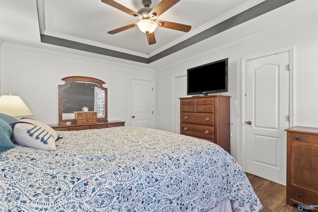 bedroom with dark wood-style floors, a tray ceiling, and crown molding