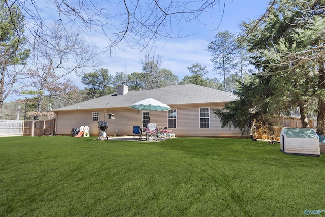 back of property featuring a shingled roof, a chimney, fence, a yard, and a patio area