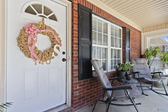 entrance to property with covered porch and brick siding