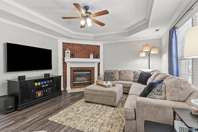 living room featuring visible vents, a ceiling fan, ornamental molding, dark wood-style floors, and a tray ceiling