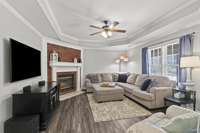 living area with ceiling fan, a tray ceiling, wood finished floors, and crown molding