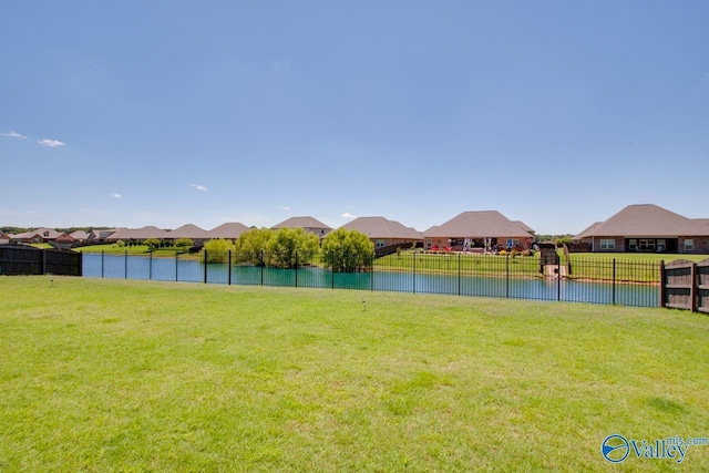 exterior space with a water view, a residential view, fence, and a yard