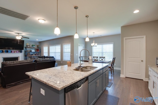 kitchen with a fireplace, visible vents, stainless steel dishwasher, dark wood-type flooring, and a sink