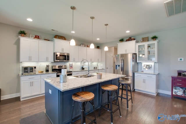 kitchen featuring visible vents, decorative backsplash, stainless steel appliances, a kitchen bar, and a sink