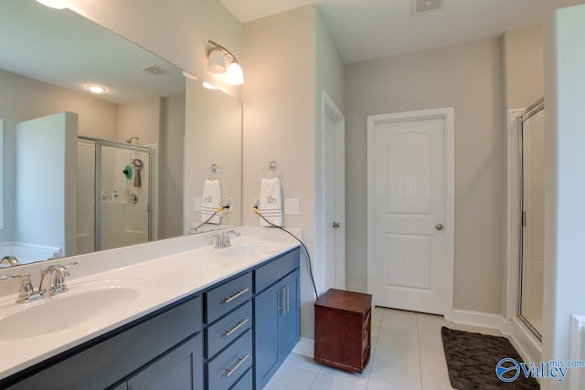 bathroom featuring double vanity, a sink, a shower stall, and tile patterned floors