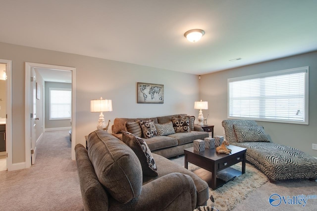 living area featuring baseboards, visible vents, and light colored carpet