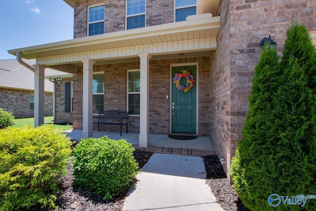 doorway to property with covered porch and brick siding