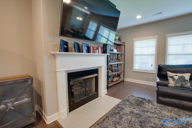 living room featuring recessed lighting, visible vents, a fireplace with flush hearth, wood finished floors, and baseboards