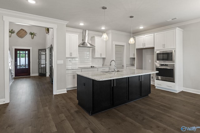 kitchen featuring dark wood-type flooring, wall chimney exhaust hood, tasteful backsplash, sink, and stainless steel appliances