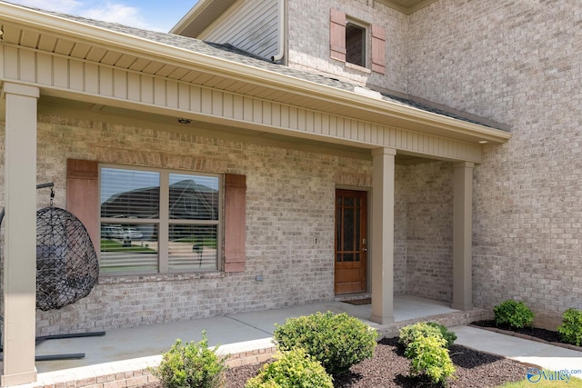 entrance to property featuring covered porch and brick siding