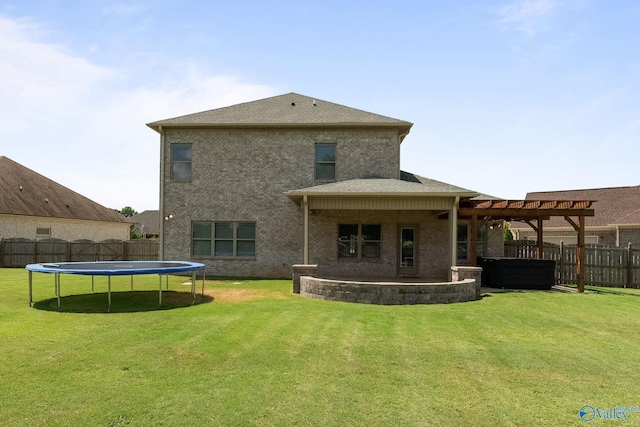 back of property featuring a trampoline, a patio, and a yard