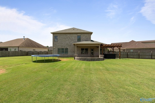 rear view of property featuring a patio area, a trampoline, a pergola, and a lawn