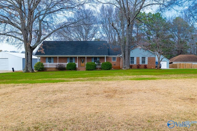 ranch-style house featuring a garage, an outbuilding, a front yard, and covered porch