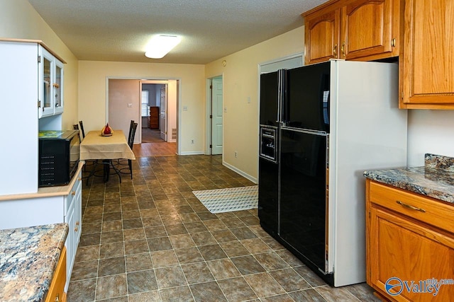kitchen featuring dark stone counters, a textured ceiling, and black appliances