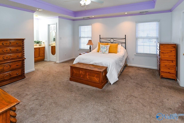 bedroom featuring ensuite bath, ornamental molding, a raised ceiling, and carpet flooring