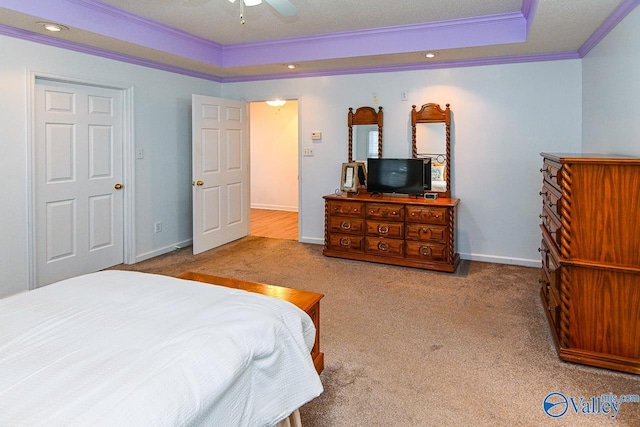 carpeted bedroom featuring ceiling fan, ornamental molding, and a tray ceiling