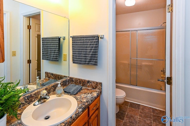 full bathroom featuring tile patterned flooring, bath / shower combo with glass door, vanity, and toilet