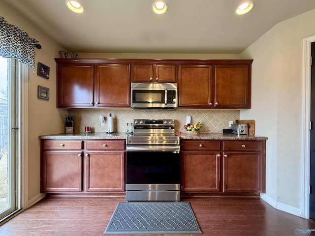 kitchen featuring vaulted ceiling, appliances with stainless steel finishes, hardwood / wood-style floors, and decorative backsplash