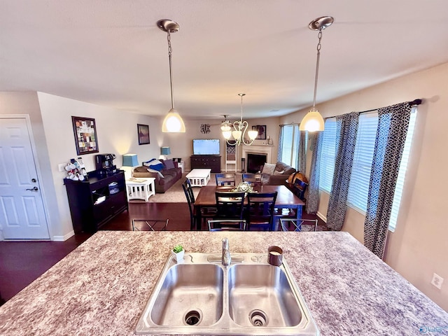 kitchen with light stone counters, decorative light fixtures, sink, and a notable chandelier