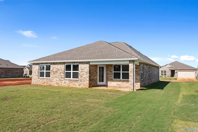 rear view of property featuring a garage and a lawn