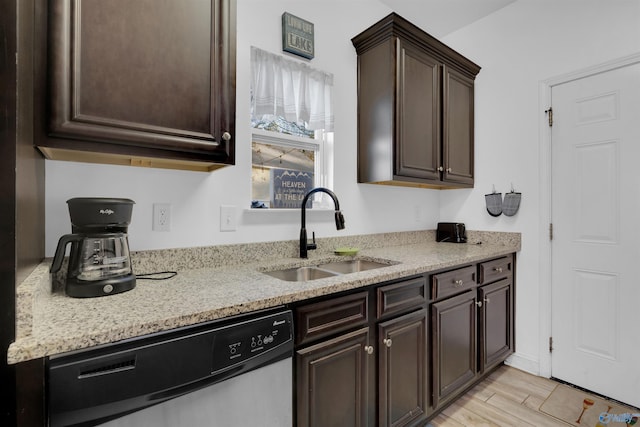 kitchen featuring light stone counters, light wood finished floors, a sink, dark brown cabinets, and dishwasher