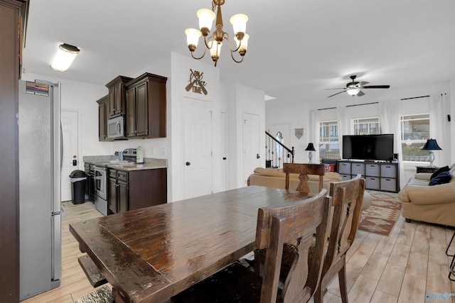 dining area with stairway, ceiling fan with notable chandelier, and light wood finished floors