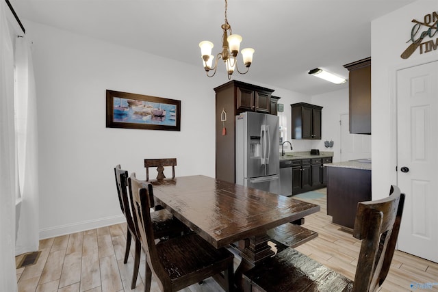 dining space featuring visible vents, baseboards, an inviting chandelier, and light wood finished floors