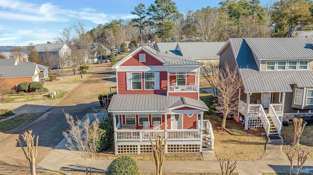 view of front of home with a balcony, covered porch, a residential view, and metal roof