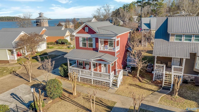 view of front of property featuring a residential view, a porch, metal roof, and a balcony