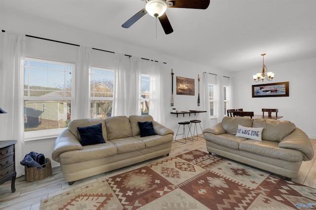 living area with plenty of natural light, light wood-style floors, and ceiling fan with notable chandelier