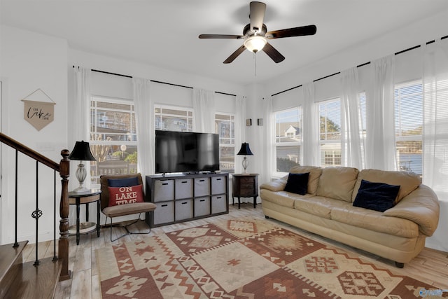 living area with stairway, ceiling fan, and wood finished floors