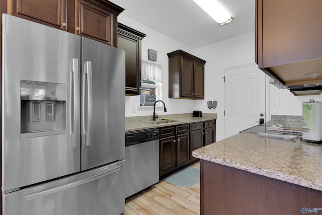 kitchen with dark brown cabinets, light stone counters, appliances with stainless steel finishes, light wood-style floors, and a sink