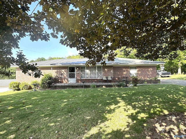 ranch-style house with brick siding, metal roof, and a front yard