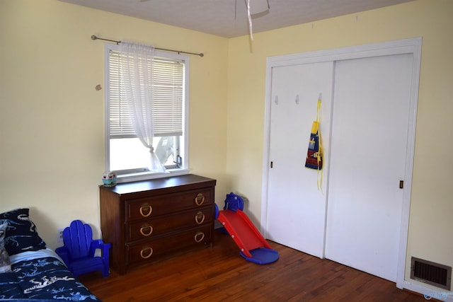bedroom with wood finished floors, visible vents, and a closet