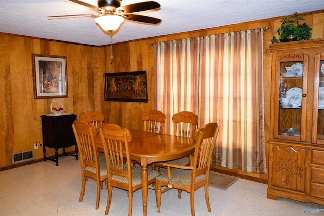 dining space featuring light floors, wooden walls, visible vents, and ceiling fan