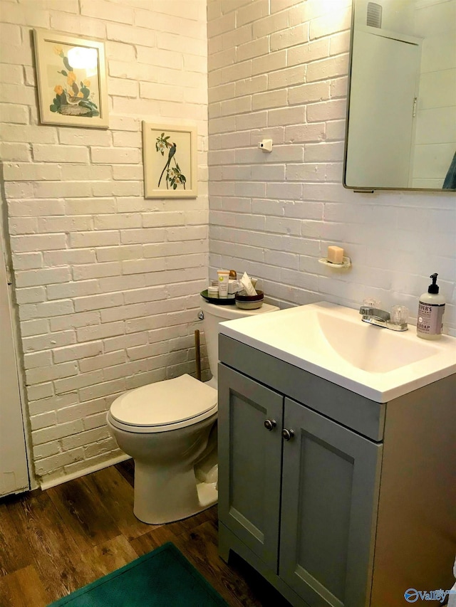 702 Mckinley Ave, Huntsville, AL 35801 - half bathroom featuring wood finished floors, toilet, vanity, and brick wall