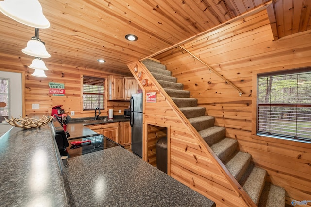 kitchen featuring dark countertops, black appliances, wooden walls, and wooden ceiling