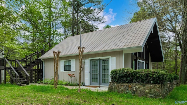 exterior space with stairs, metal roof, and a lawn