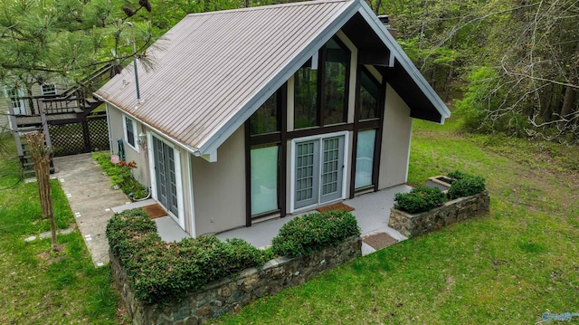 exterior space featuring metal roof, a yard, a standing seam roof, and stucco siding