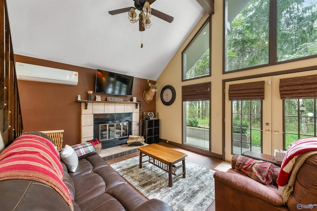 living area with high vaulted ceiling, a tile fireplace, a ceiling fan, an AC wall unit, and french doors