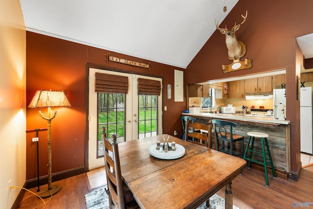 dining room featuring vaulted ceiling, wood finished floors, and french doors