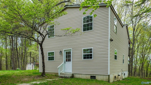 rear view of property with crawl space, a storage unit, an outdoor structure, and entry steps